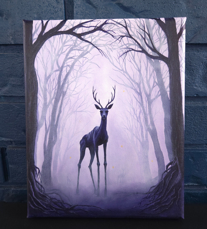 Framed artwork of a silhouette of a deer-like creature in a forest setting.