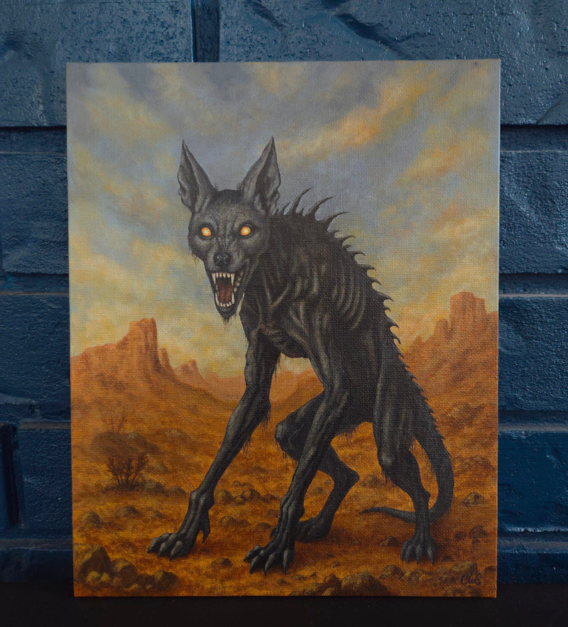 Painting of a dark, otherworldly chupacabra creature in a desert landscape against a brick wall.