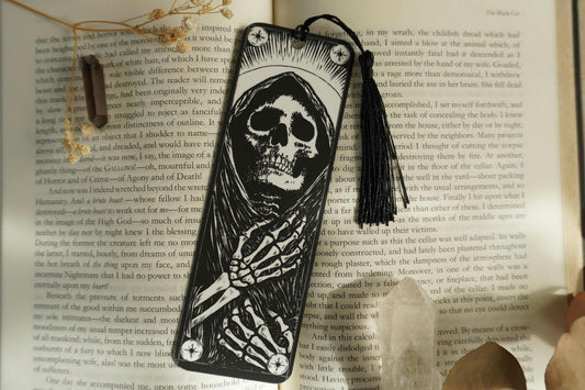 black and white grim reaper skeletal figure bookmark with tassel on an open book